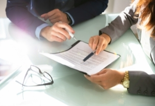 Business professionals discussing and reviewing a document at a desk – NRIWAY company services.